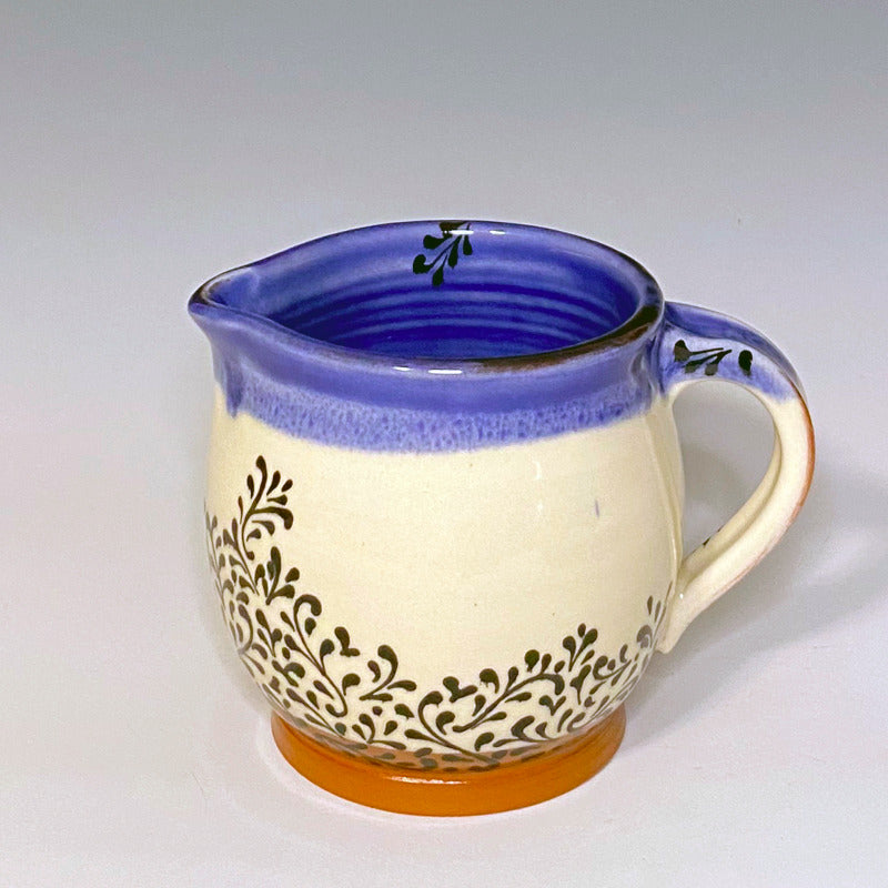 Handled creamer set. Red earthenware clay with white background, blue inside, and black scroll decoration.
