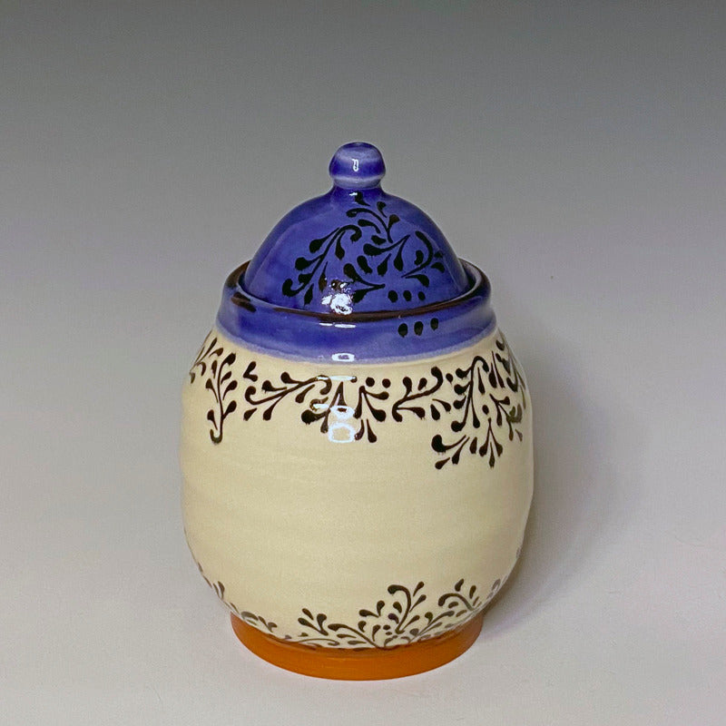 Lidded sugar jar. Red earthenware clay with white background, blue inside, and black scroll decoration.